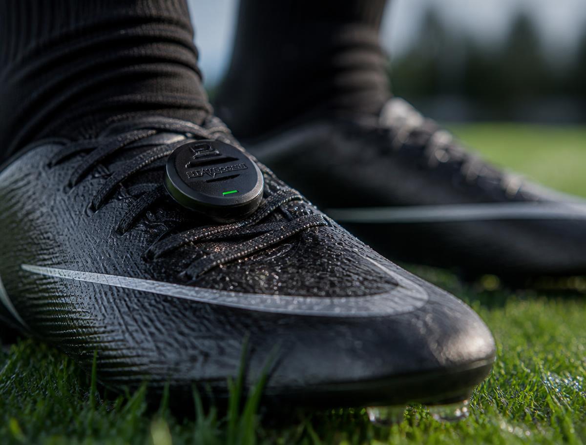 Football boots on grass with a small sensor attached to the laces
